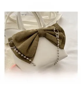 Détail du sac blanc avec nœud en daim vert olive et décor de chaîne à billes argent