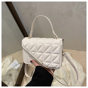 Close-up of cream quilted handbag featuring gold metal trim and diamond stitch detail