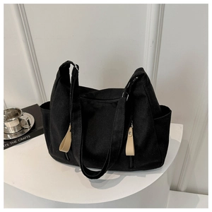 Detail of black canvas tote bag with side pocket and long pull zipper on a pedestal
