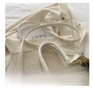Détail de la bandoulière réglable et du grand nœud en velours vert sur un sac blanc