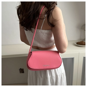 Detail view of pink leather shoulder bag with Fashion lettering and curved flap design