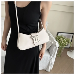 Close-up of cream-colored leather shoulder bag with gothic M-shaped silver buckle detail