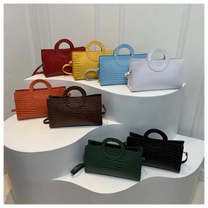 Various colors of crocodile pattern crossbody bags displayed on a white tiered stand