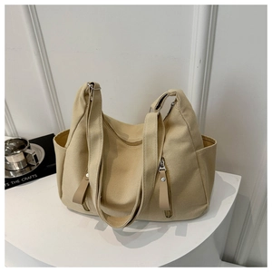 Detail view of large khaki canvas tote bag featuring front vertical zipper pockets