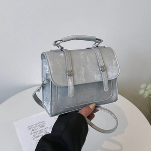 Silver pearlescent crossbody bag with a sleek metallic texture and top handle