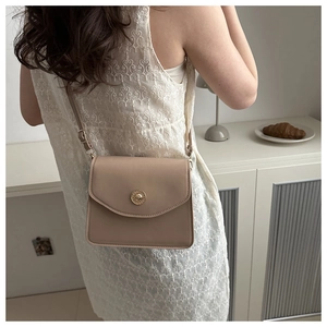 Détail d'un sac à bandoulière en cuir beige minimaliste avec boucle ronde en métal