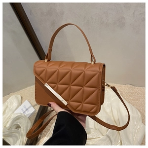 Close-up of brown quilted faux leather handbag with elegant gold metal bar detail