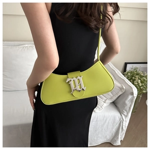 Detail of lime green leather baguette bag with silver gothic M buckle on shoulder