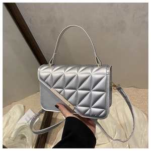 Detail showing silver quilted texture and metallic buckle on handbag with handle