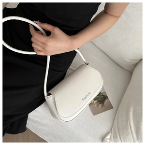Minimalist white leather shoulder bag with Fashion lettering shown on a black dress