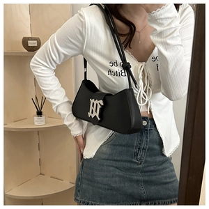 Close-up of black leather underarm bag featuring a silver metal M-shaped buckle detail