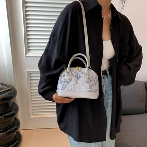 Gray shell shoulder bag with landscape pattern and golden hardware shown on a model
