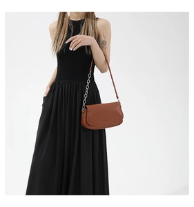 Detail of silver chain strap on a brown matte leather crescent shoulder bag