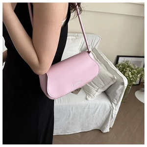 Close-up of pink faux leather shoulder bag featuring 'Fashion' print in a home setting