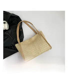 Detail view of woven straw tote bag with contrasting dark brown faux leather handles