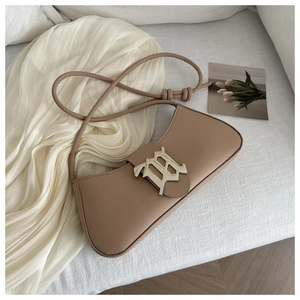 Detail of light brown leather underarm bag with gold M-logo buckle and knot strap