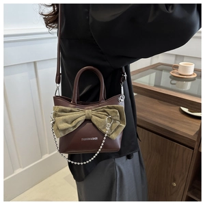 Détail d'un sac seau marron vintage avec nœud vert et chaîne à perles argentées chic