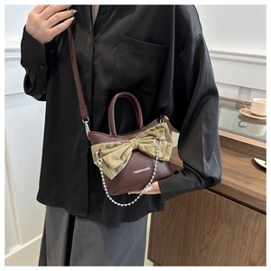 Detail view of a vintage brown leather bucket bag with a chic bow and metal chain accent