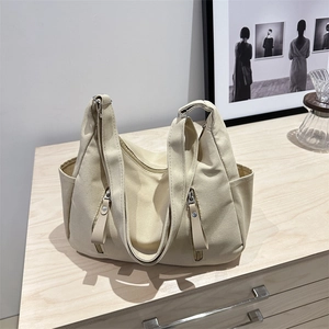 Minimalist off-white canvas tote bag with multi-pocket design on a wooden table
