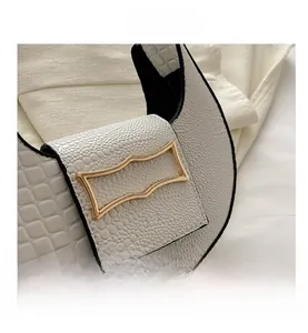 Close-up of white crocodile pattern crescent bag with an irregular gold metal buckle