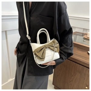 Détail d'un mini sac blanc orné d'un grand nœud olive et d'une chaîne argentée