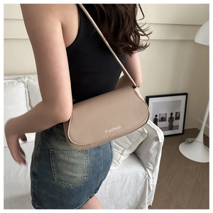 Close-up of minimalist beige baguette bag with Fashion lettering on leather flap