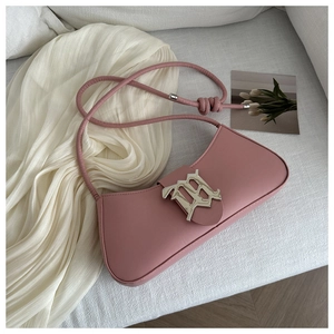 Detail of pink baguette bag with leather strap and metal M buckle on white fabric