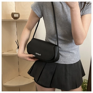 Close-up of minimalist black leather oval shoulder bag with Fashion logo print