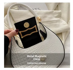 Close-up of white crocodile pattern shoulder bag with a gold hardware magnetic snap