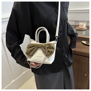 Detail of white bucket bag with green bow, silver chain, and fashion crossbody strap
