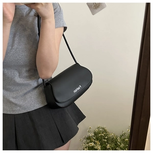 Detail of a black crescent crossbody bag with a matte finish and Fashion lettering