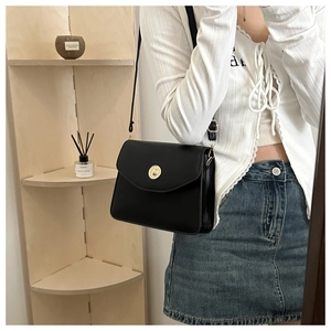 Détail d'un sac à bandoulière noir vintage avec une boucle métallique dorée circulaire