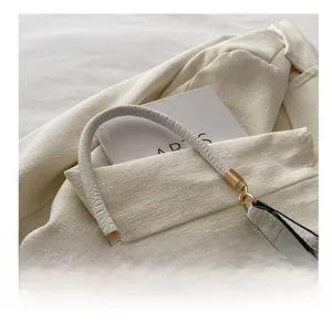 Detail of white animal print handbag handle with golden hardware on a blazer