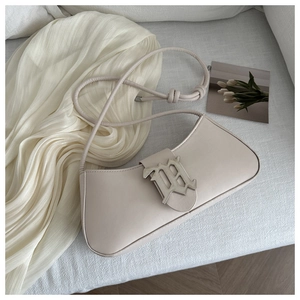 Detail of a beige leather Hobo bag featuring a large silver M buckle and a slim strap