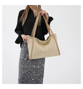 Close-up of beige woven straw tote bag with brown leather handles and spacious interior