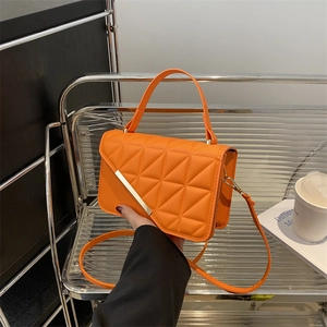 Bright orange quilted handbag with triangular stitching and gold metal bar accent