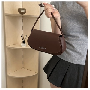 Detail of dark brown matte leather underarm bag with Fashion lettering and curved flap