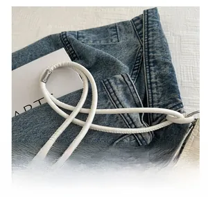 Detail view of woven texture and slim round shoulder strap on creamy white shoulder bag