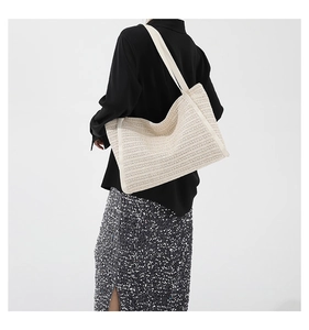 Detailed view of woven straw tote bag texture and wide shoulder strap design
