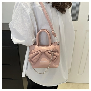Close-up of pink mini bucket bag with a large suede bow and decorative silver bead chain