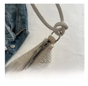 Detailed view of white woven leather texture with smooth silver zipper and knotted handle strap