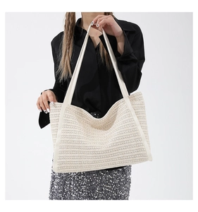 Detail of the woven texture and white leather straps on this straw tote bag