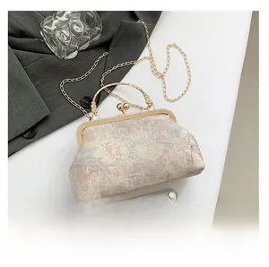 Detailed macro view of vintage floral brocade clutch bag with golden metal handle and chain