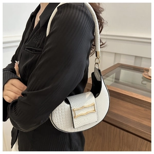 Detail of white hobo bag with crocodile texture and gold metal buckle on black clothing