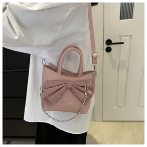 Détail du sac bandoulière rose avec grand nœud décoratif et chaîne à boules élégante