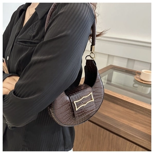 Detail of chocolate crocodile pattern crescent bag with unique gold metallic buckle