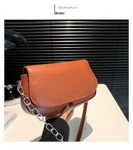 Detail of brown faux leather crossbody bag featuring silver chain and embossed logo