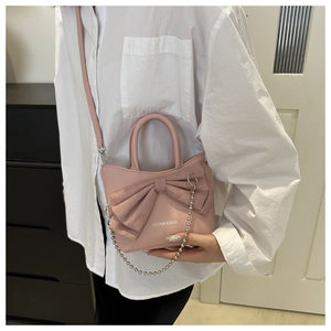 Detail of pink mini bucket bag featuring a large bow and silver bead chain accessory