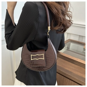 Detail of dark brown faux crocodile leather crescent bag with metallic gold buckle