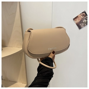 Close-up of minimalist beige leather saddle bag featuring fashion typography and flap closure